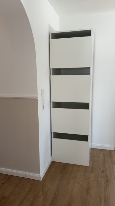Schmaler, moderner Schrank mit vier Schubladen in einem hellen Raum.