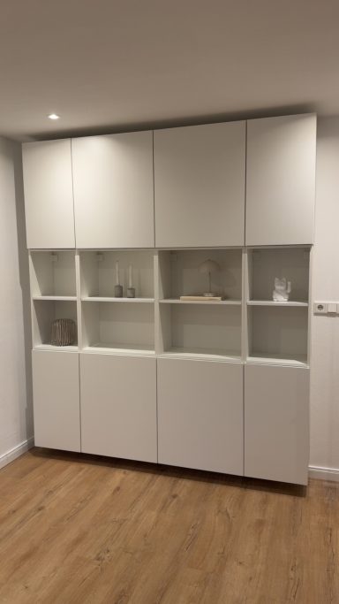 Weißes Möbelstück mit Glaselementen und Holzfußboden im Hintergrund.