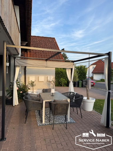 Gartenpavillon mit Essbereich, Tisch und Stühlen, umgeben von Pflanzen. Möbelaufbau Amberg